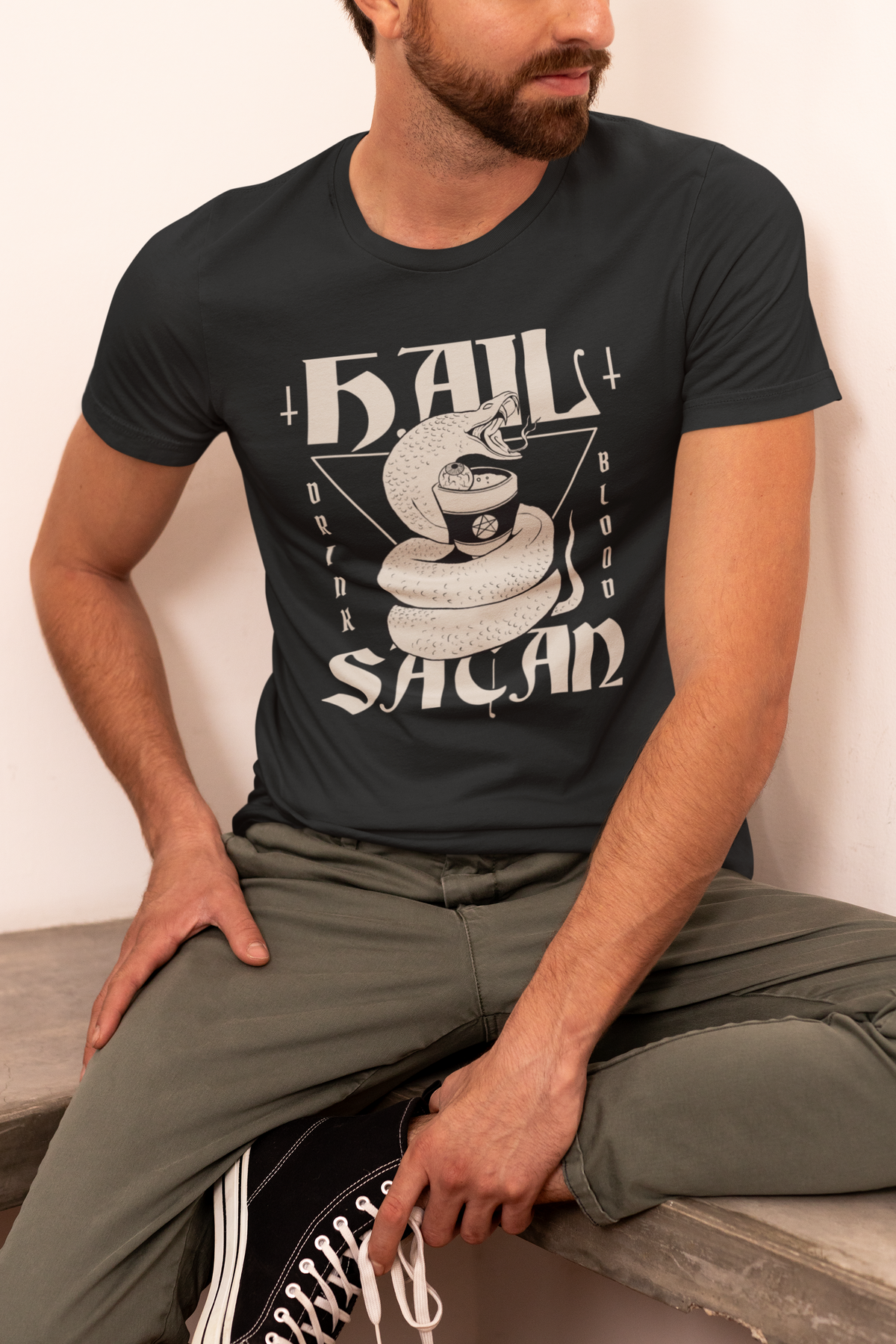 'Hail Satan' snake t-shirt in black, man sitting outdoors wearing it