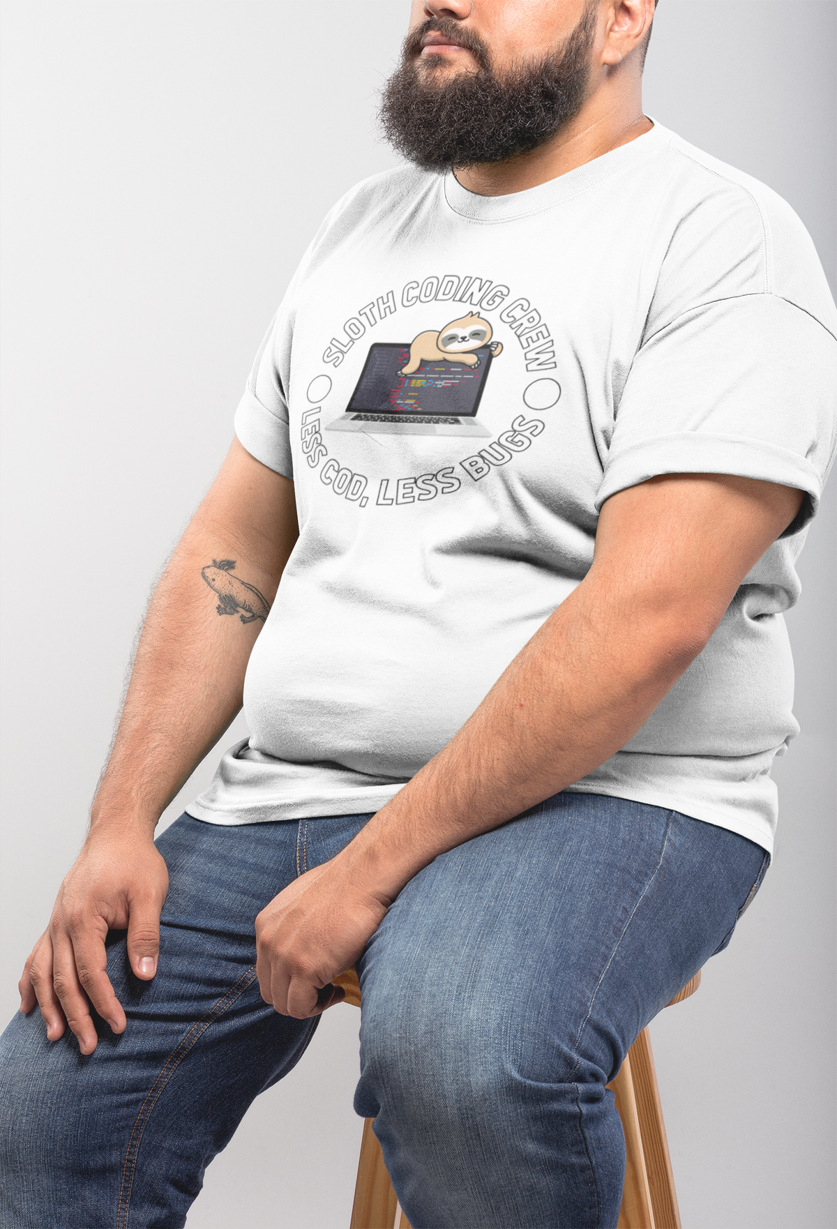 'Sloth Coding Crew' badge T-shirt in white, man sitting sideways wearing it, programmer gift tee