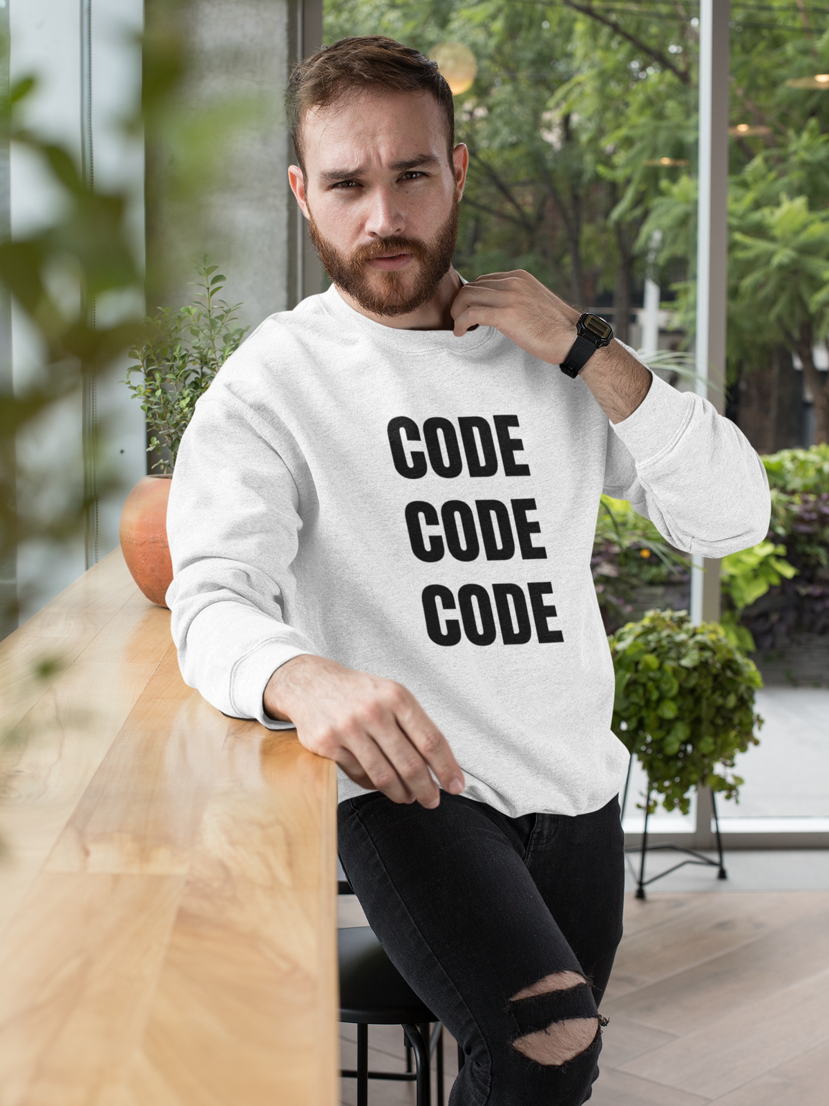 "Code Code Code" sweatshirt in white, bearded man sitting near a window, funny developer gift sweatshirt