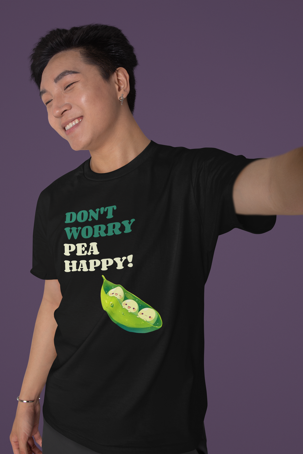 'Don't Worry Pea Happy' pea pun t-shirt in black, man wearing it, purple backdrop, funny pun gift