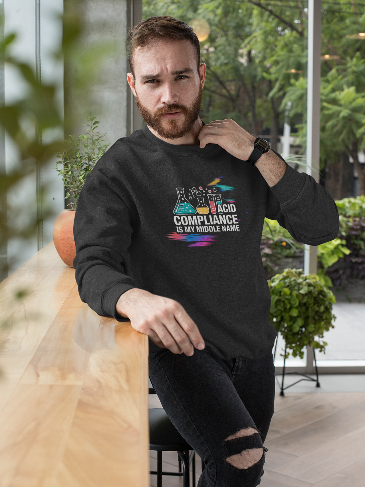 'ACID Compliance Is My Middle Name' sweatshirt in black, man wearing it on a chair, funny database engineer gift