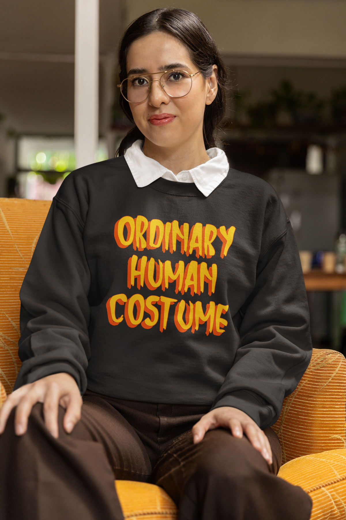 'Ordinary Human Costume' funny halloween sweatshirt in black, woman sitting indoors, funny costume gift