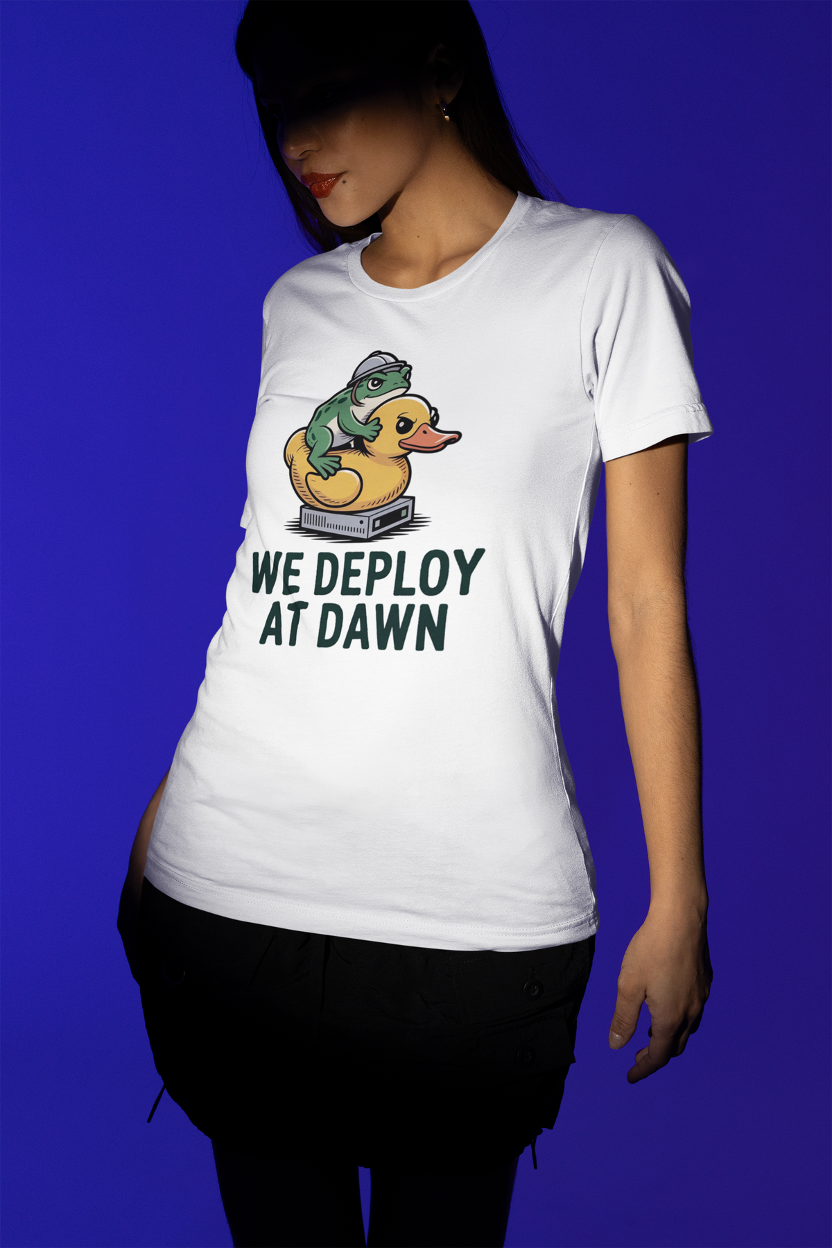 'We Deploy at Dawn' tee in white, woman wearing it on blue background, coder gift idea