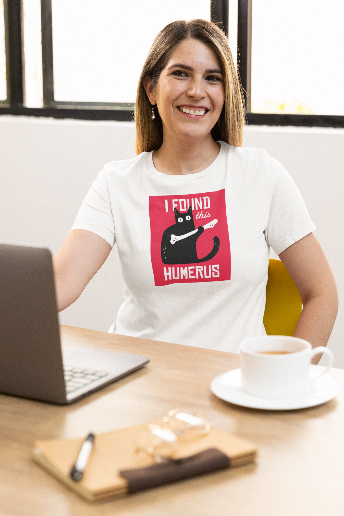 'I Found This Humerus T-Shirt' in white, woman at an office desk, T-Shirt mockup, Geekpsters