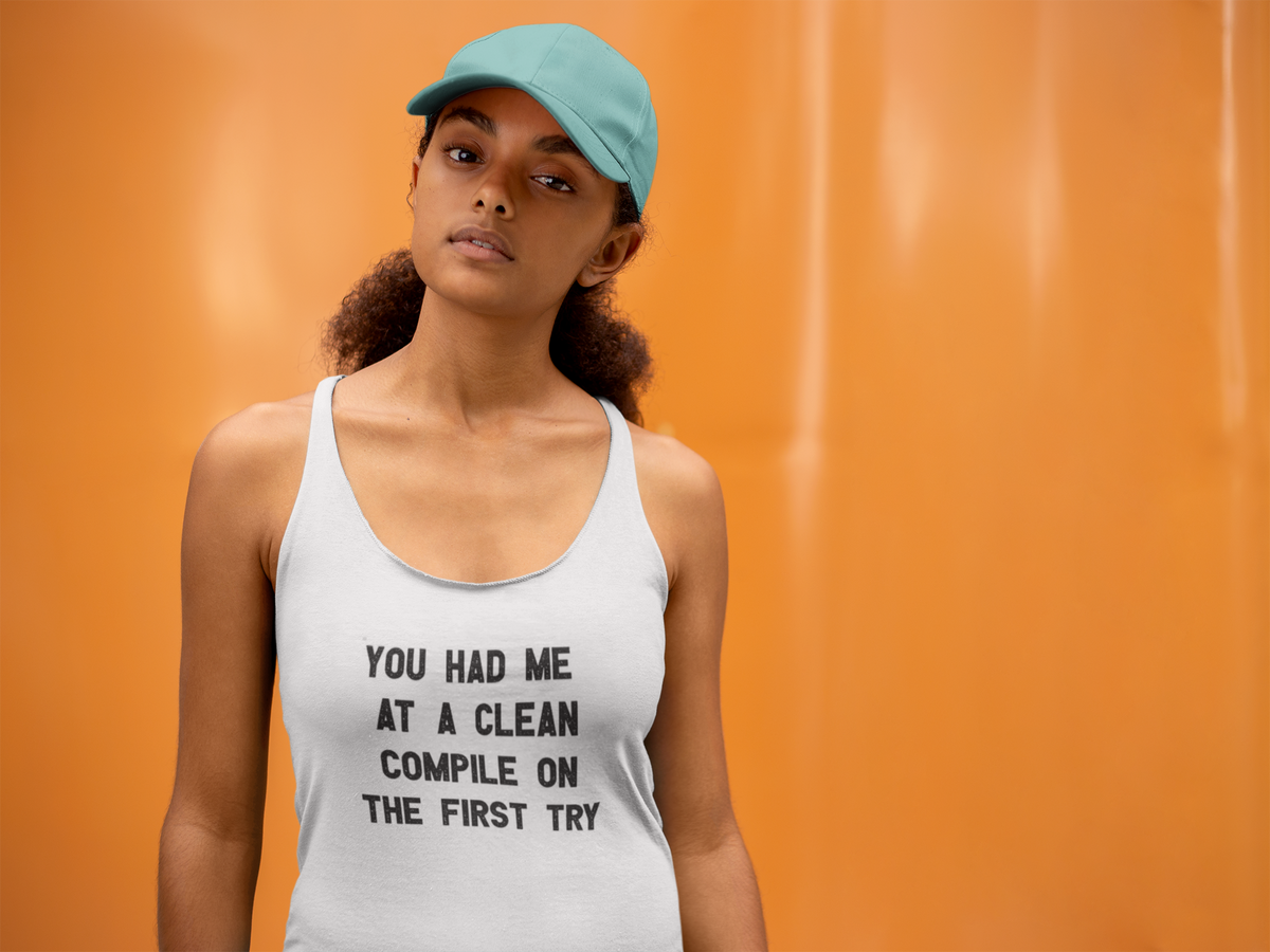 'Clean Compile' racerback tank top in white, woman wearing it by an orange wall, Tank Top mockup, Geekpsters
