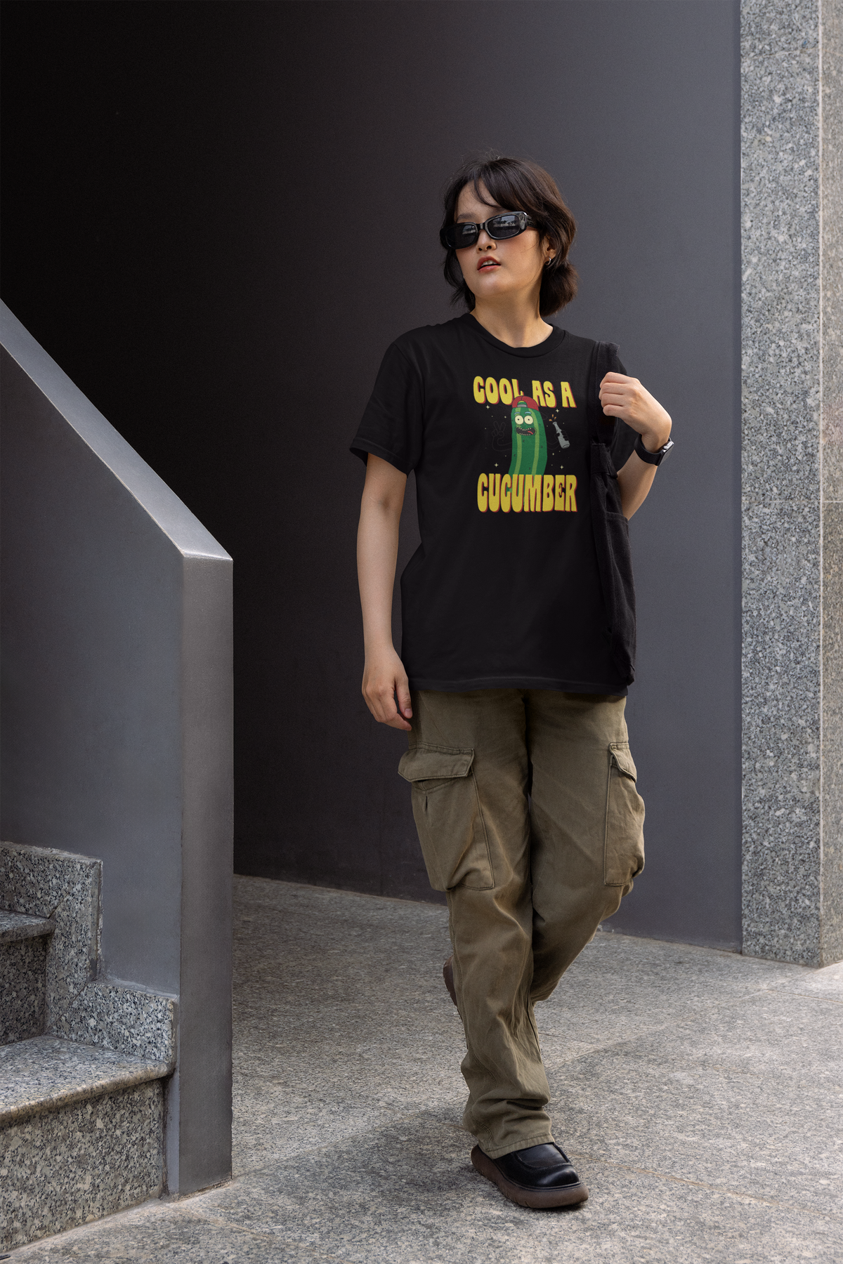 "Cool As A Cucumber" cartoon graphic tee in black, man walking wearing it in cargo pants, funny gift