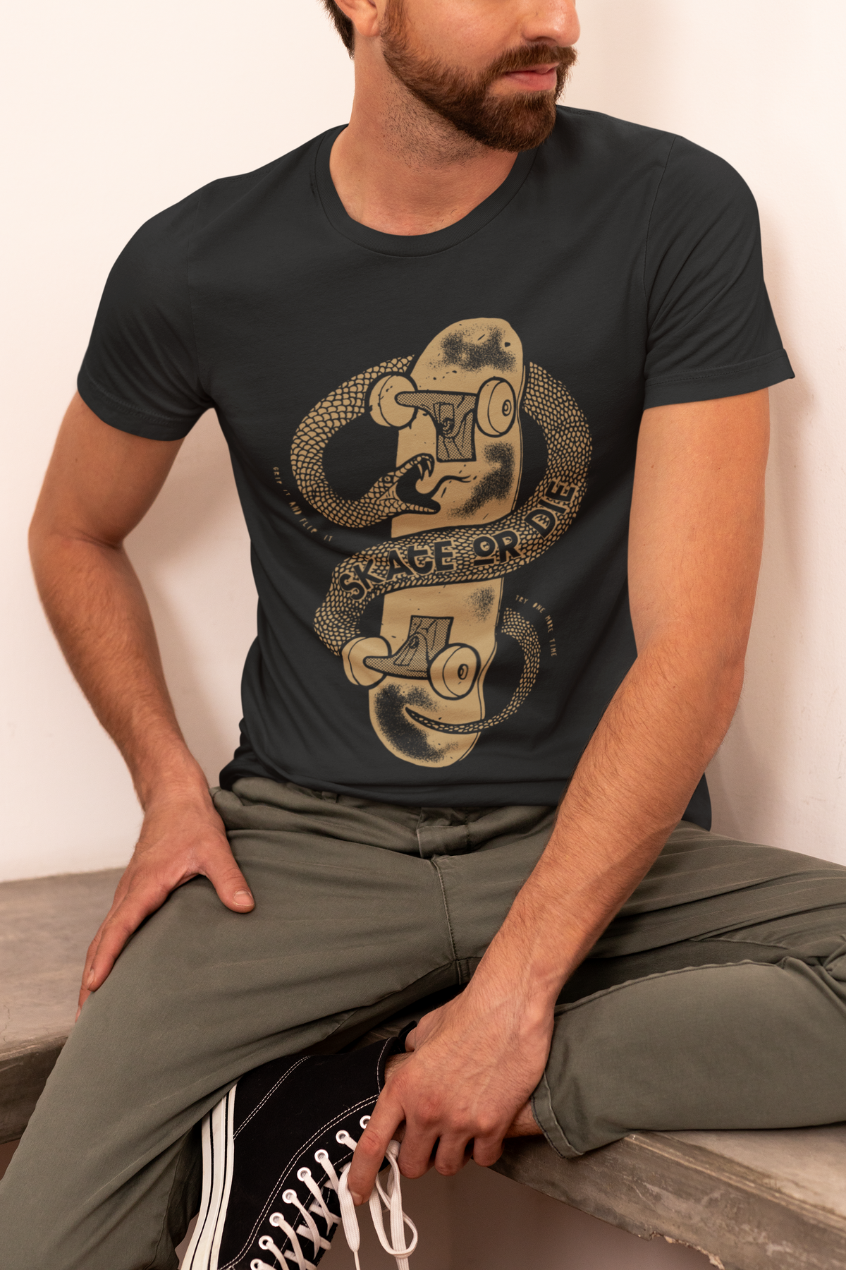 "Skate or Die" snake and skateboard t-shirt in black, man wearing it kneeling, edgy skater gift