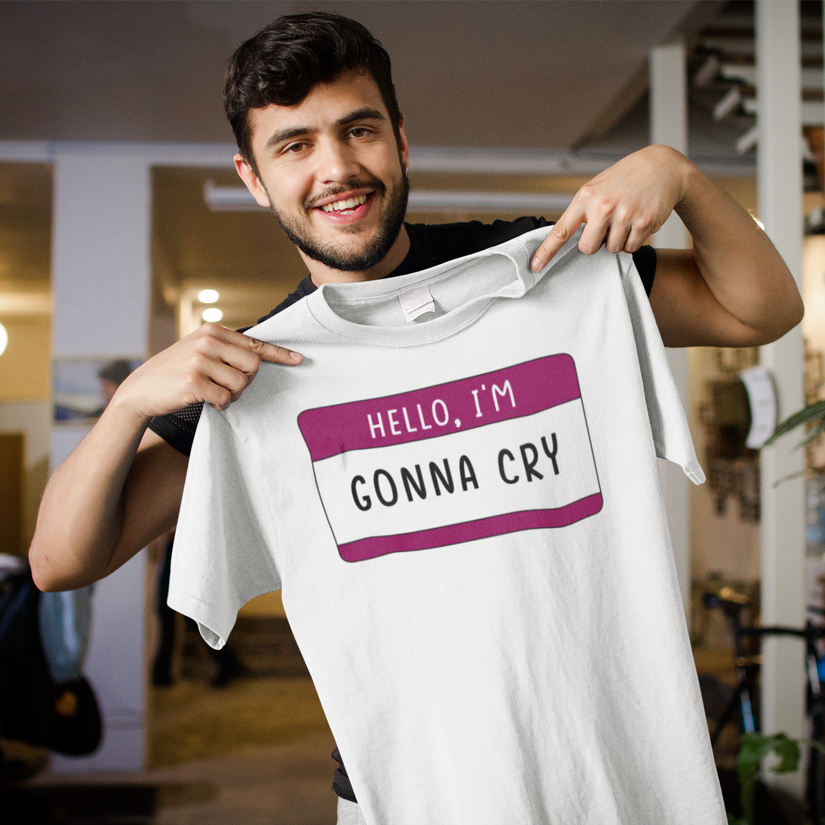 Hello I'm Gonna Cry name tag T-shirt in white, man holding it up on a city street, sarcastic gift tee