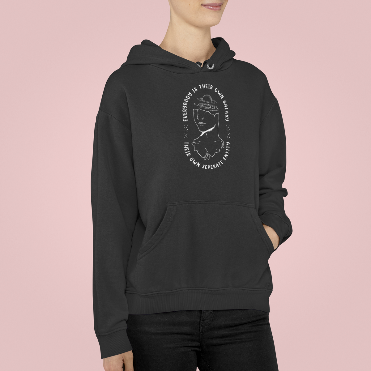 'Everybody Is Their Own Galaxy' illustrated hoodie in black, flat lay on pink background, inspirational gift
