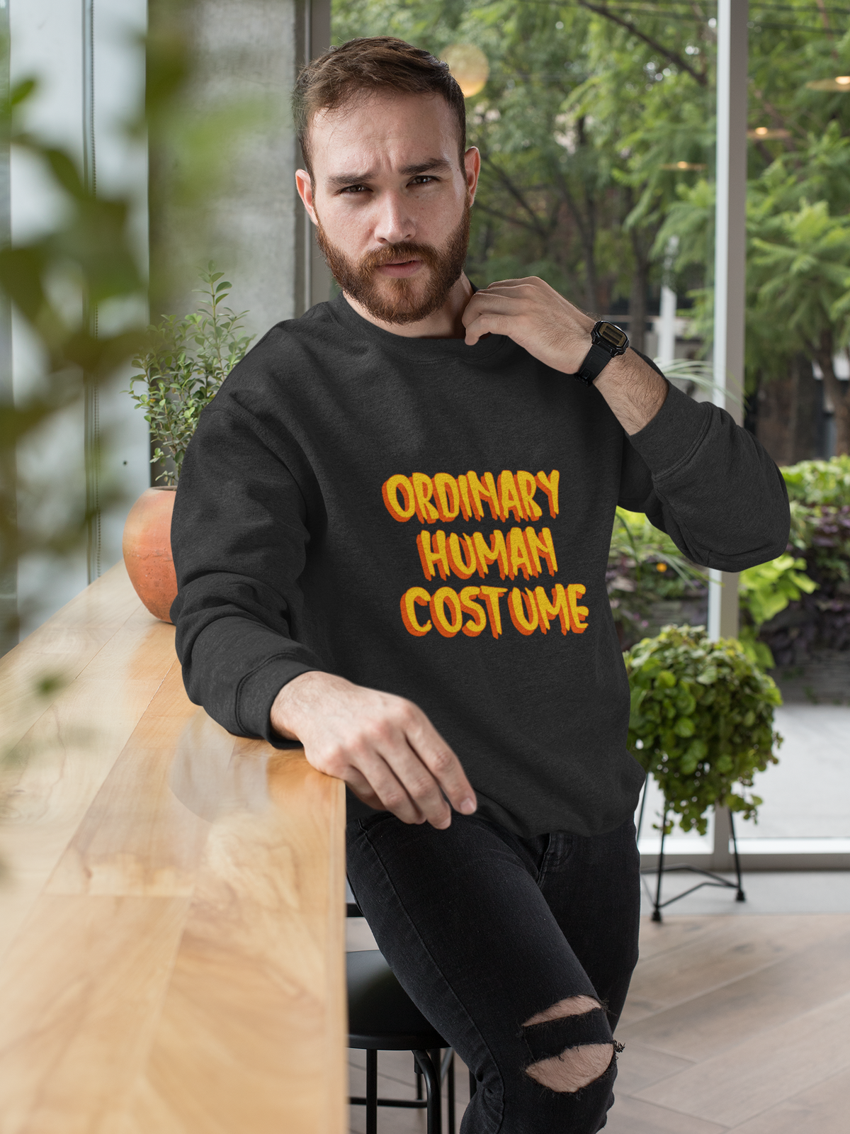 'Ordinary Human Costume' funny halloween sweatshirt in black, bearded man sitting indoors, funny gift
