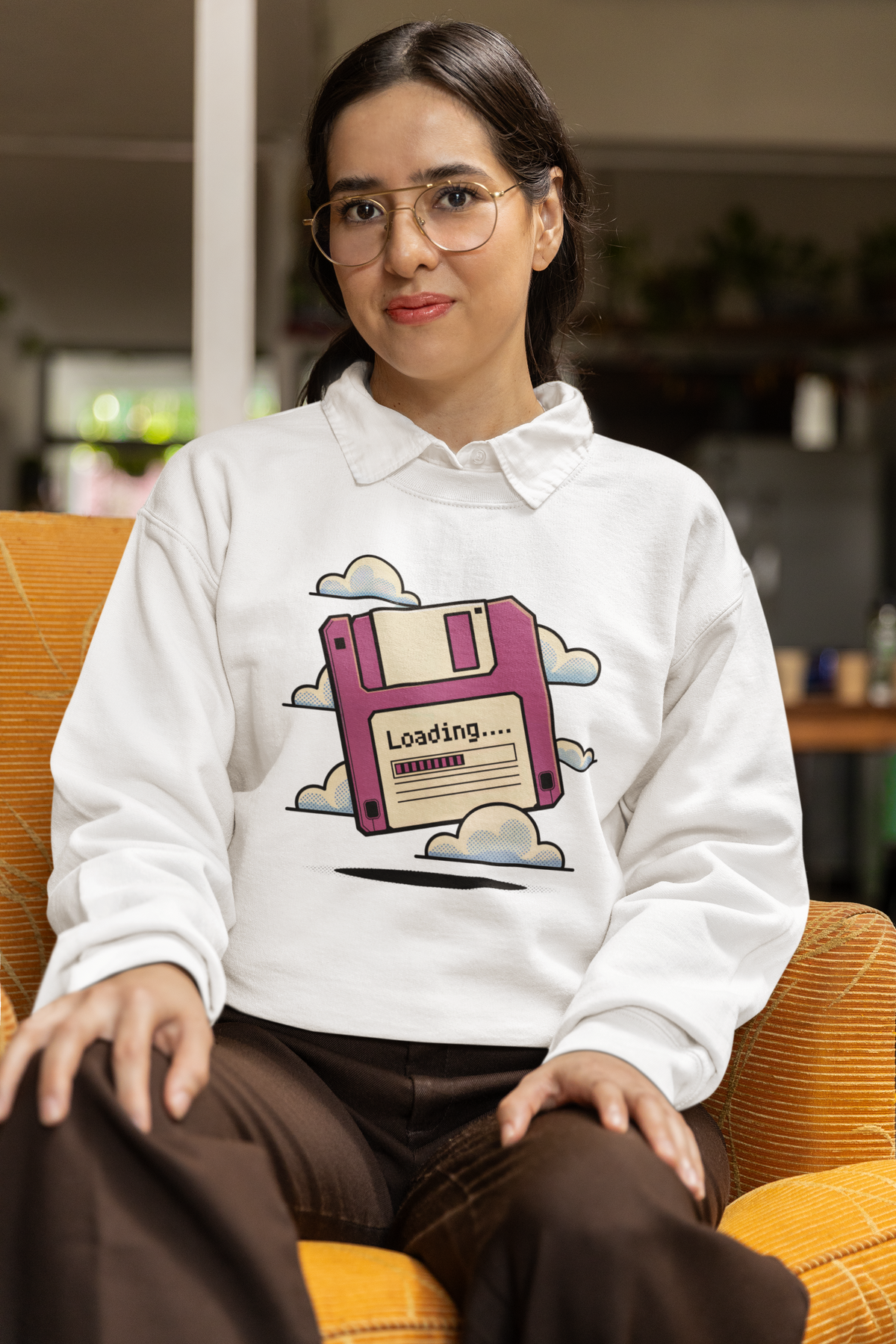 'Loading' floppy disk sweatshirt in white, woman sitting wearing it indoors, funny developer gift