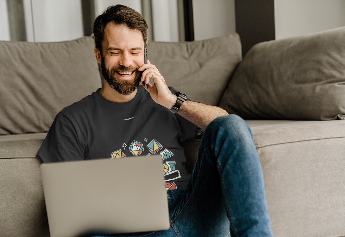 'Cat Dice' t-shirt in black, man wearing it while on a phone call at home, funny tabletop gamer gift