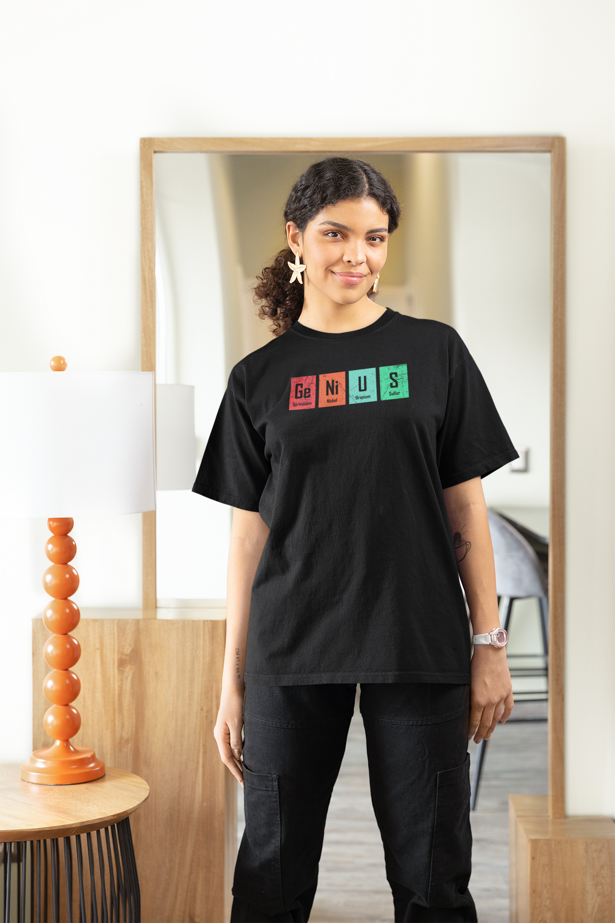 'Genius' periodic table pun women's tee in black, woman wearing it at home, funny science pun tee