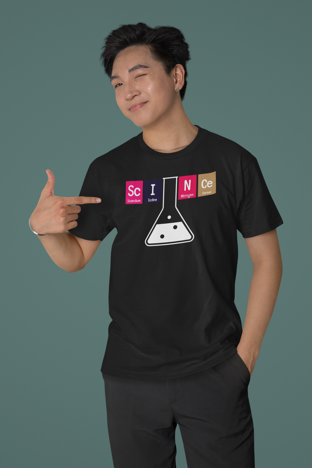 'Science' periodic table t-shirt in black, smiling man pointing at it, teal backdrop, funny science pun gift
