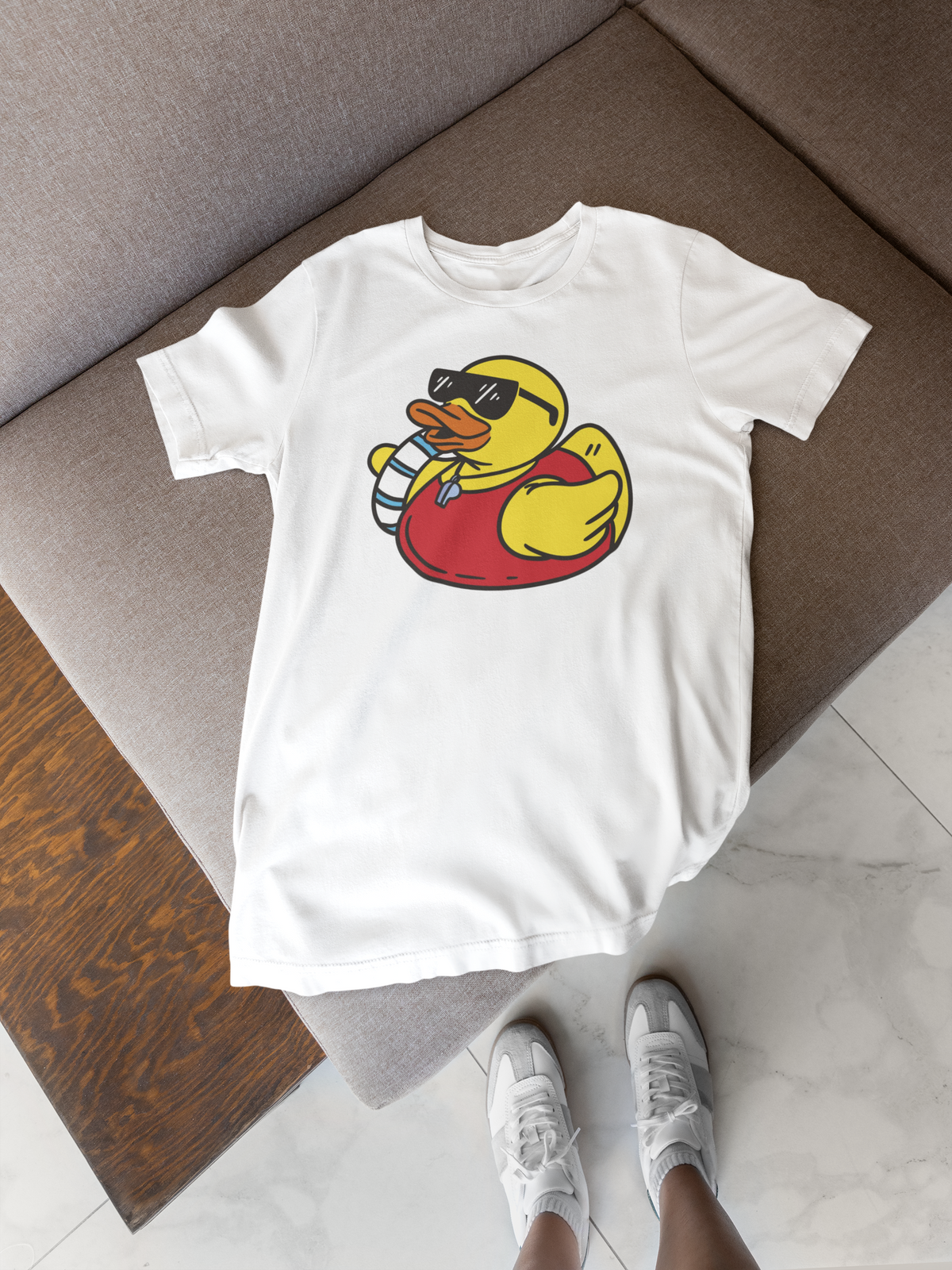 Life saver duck t-shirt in white, flat lay on a wooden floor with sneakers, funny summer gift shirt