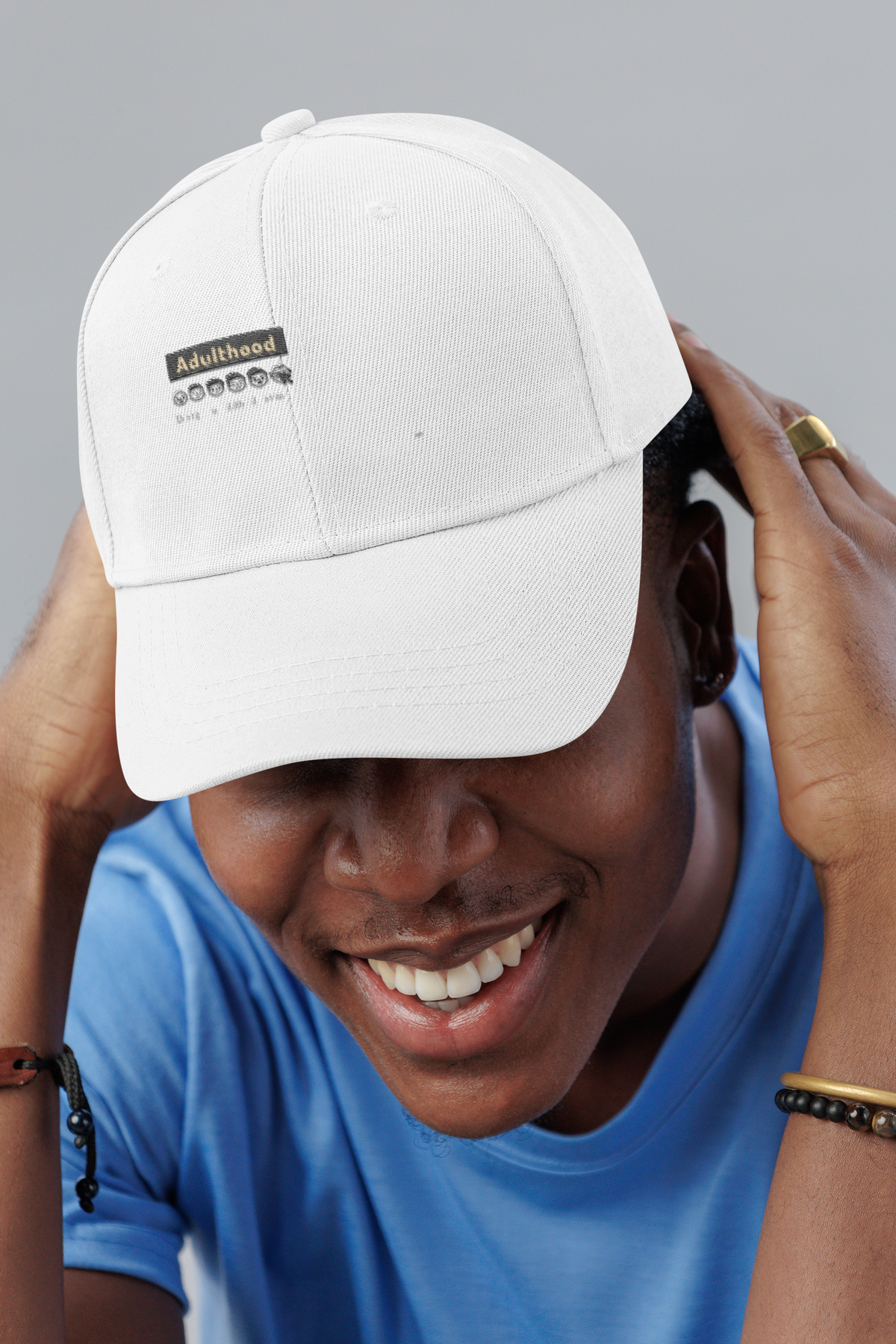 Adulthood is a Trap sarcastic dad hat, smiling man in a studio, lifestyle mockup, Geekpsters