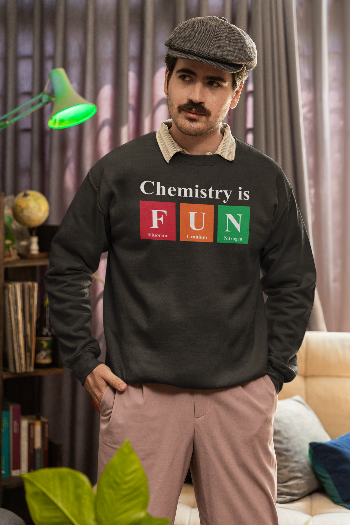 'Chemistry is FUN' crewneck sweatshirt in olive green, man wearing it indoors with newsboy cap, funny chemistry pun gift
