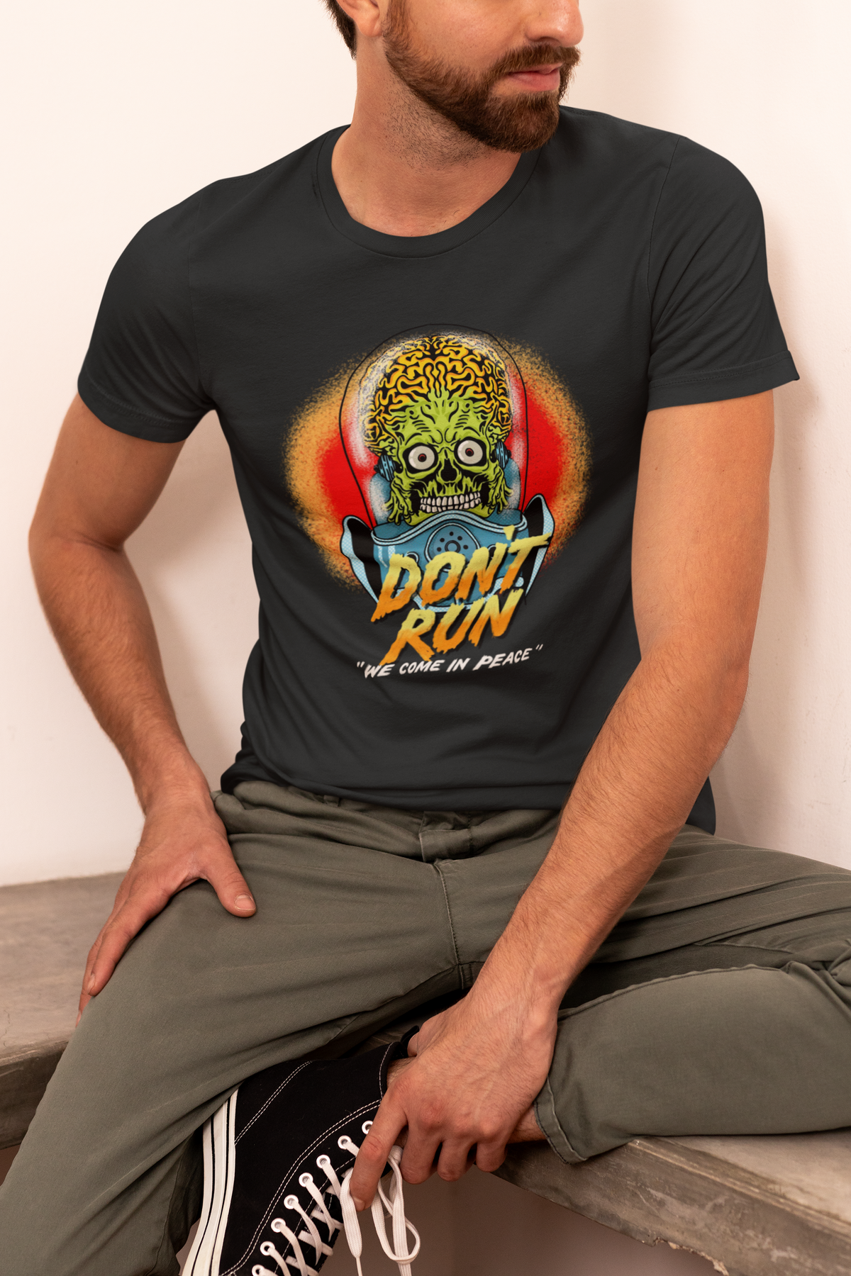 'Don't Run' alien t-shirt in heather black, man sitting outdoors wearing it, sci-fi fan tee