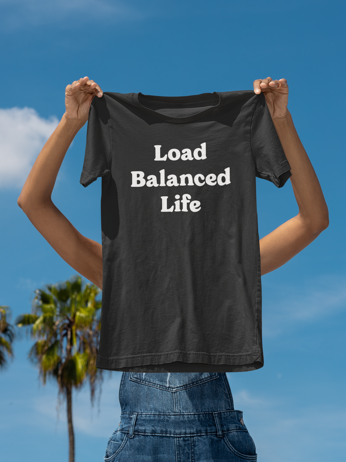 'Load Balanced Life' t-shirt in black, person holding it up outdoors, funny gift for network engineers