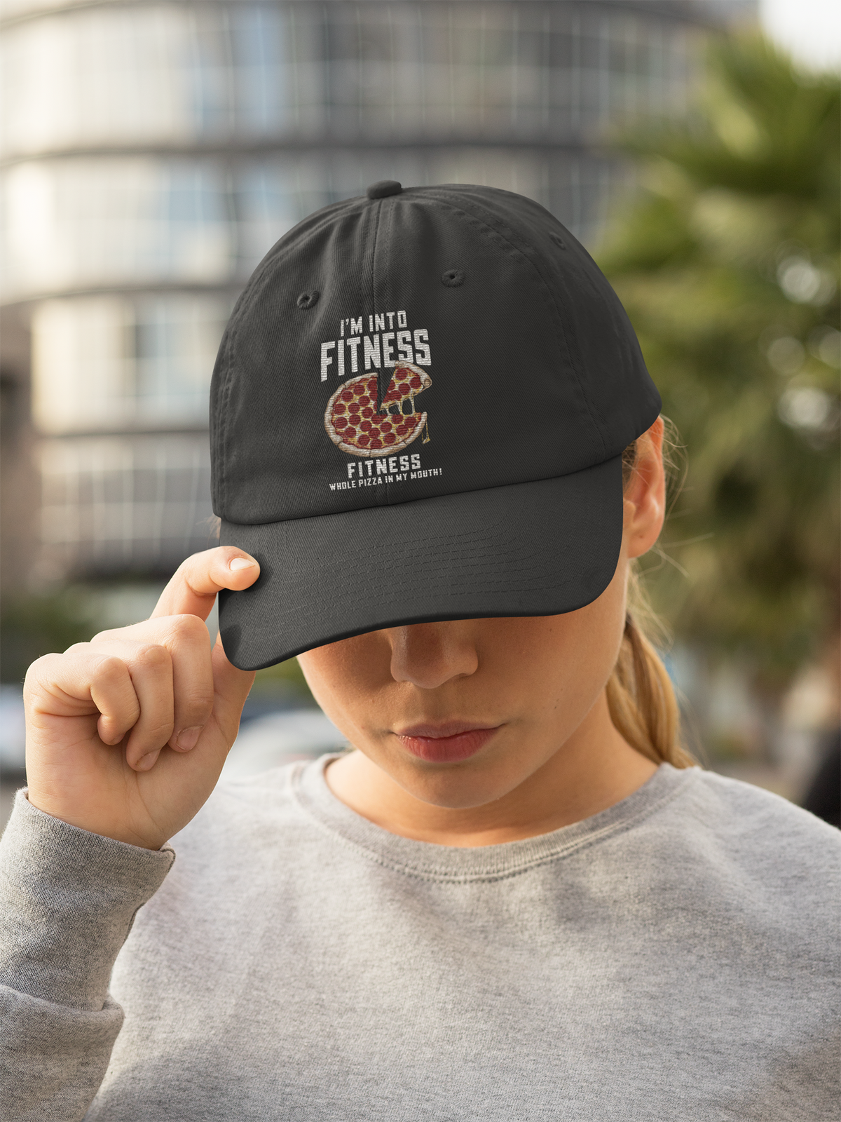 'I'm Into Fitness' pizza slice dad hat in black, woman wearing it in the city, funny foodie gift idea