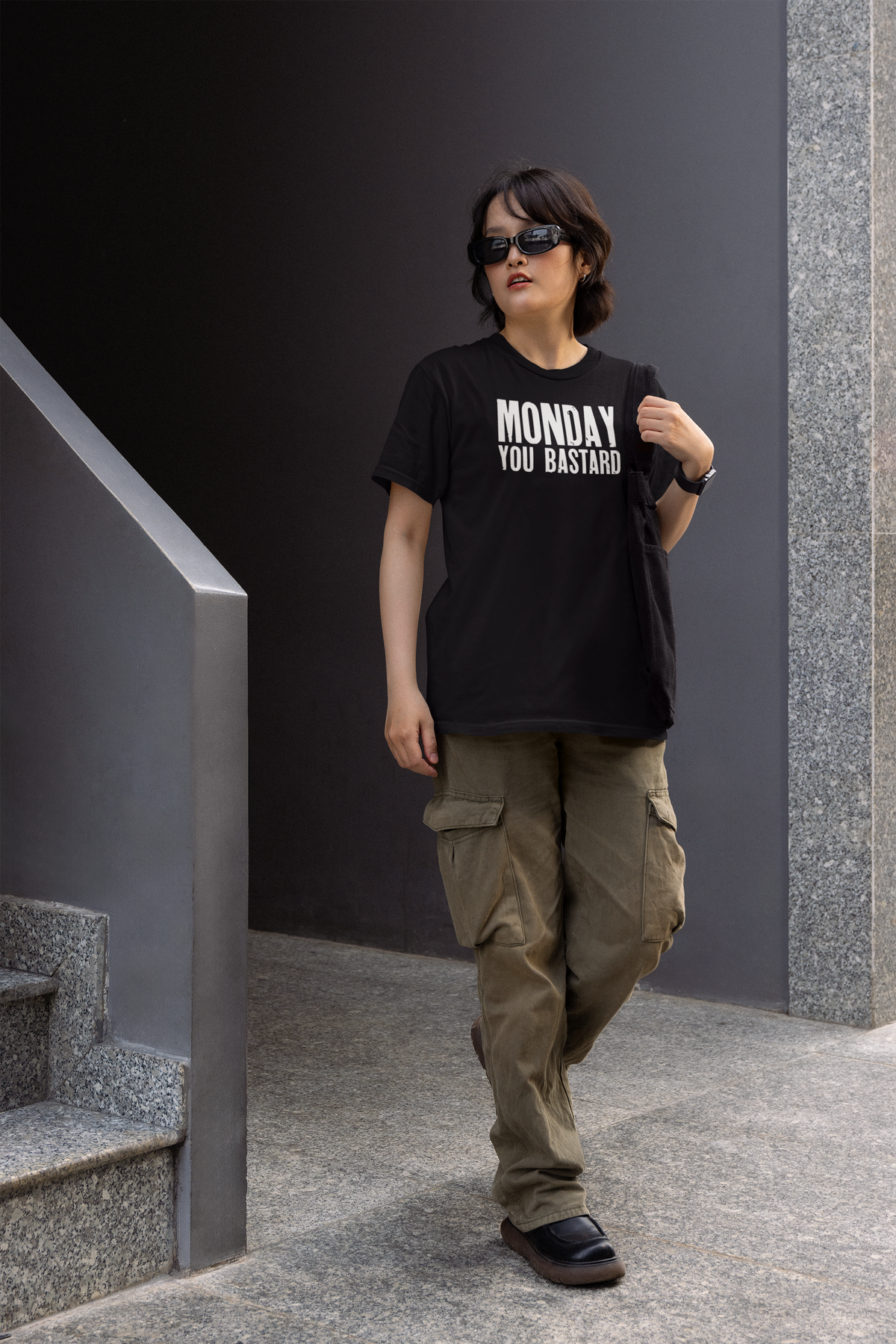 'Monday You Bastard' women's t-shirt in black, woman wearing it on stairs outdoors, sarcastic office gift
